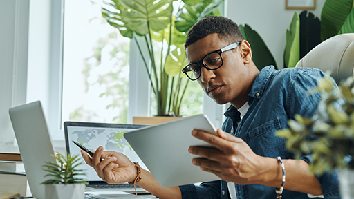 Man comparing information on tablet to his laptop