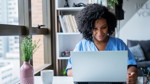 Image of a woman sitting at desk in an urban setting looking at a laptop.